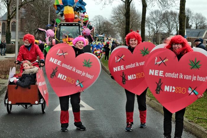 Vier deelnemers aan een carnavalsoptocht dragen grote, rode harten met daarop de tekst: 'Nee, omdat ik van je hou! NIX18'. Op de harten staan ook doorgekruiste afbeeldingen van drank, sigaretten en drugs.